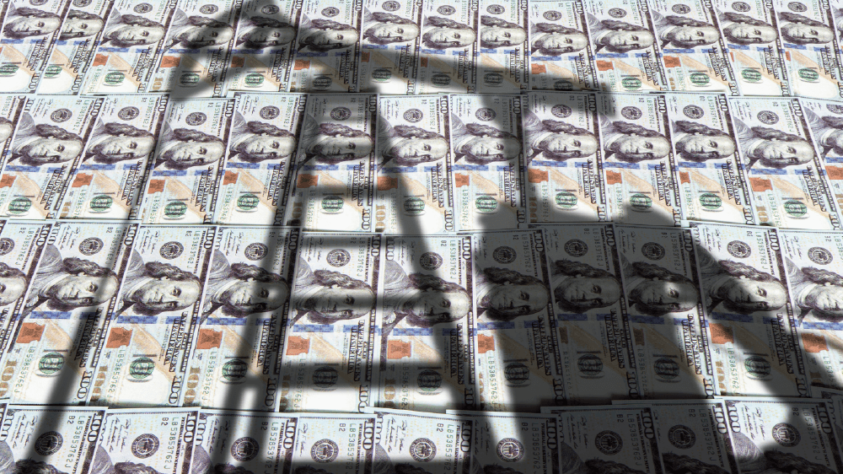 US cash with the shadow of an oil rig over it