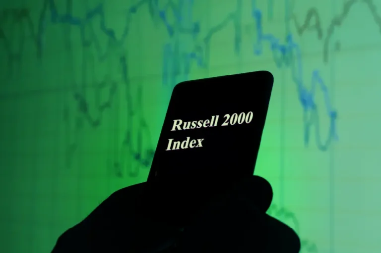 Silhouette of a cell phone that says "Russell 2000 Index" on a green background with financial charts on it