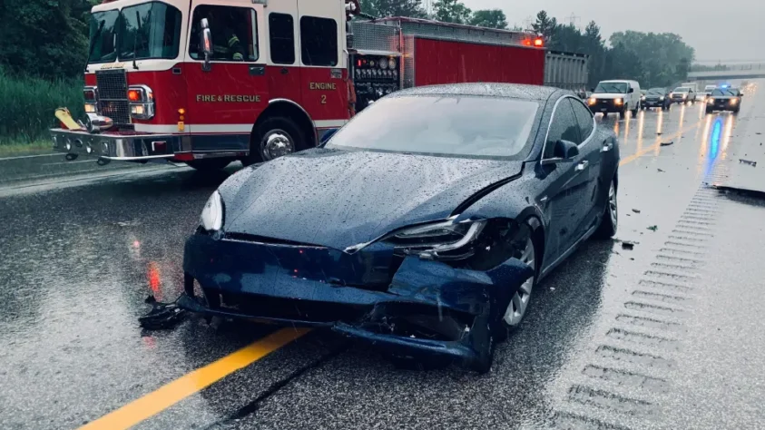 A navy blue Tesla crashed on a rainy highway