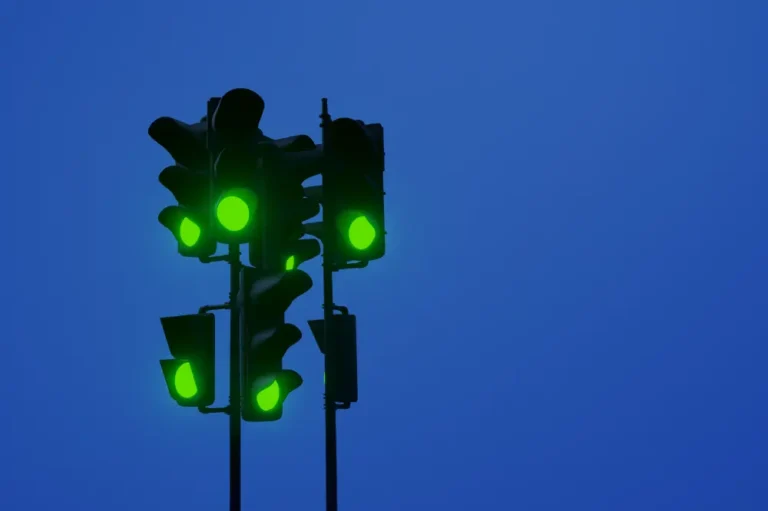six traffic lights all showing green, on a dark blue sky background